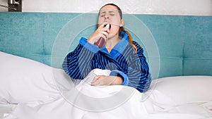 Portrait of sick young woman using throat spray to reduce pain