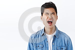 Portrait of silly asian young man whining like baby, crying and screaming complaining on cruel unfair life, close eyes