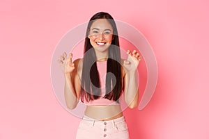 Portrait of silly and cute, upbeat asian girl in trendy summer clothes having fun, acting like lion, making roar gesture