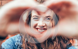 Portrait of sincerely smiling red curled long hair caucasian teen girl with applied red lipstick lips with blue eyes making a