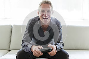 Portrait of single 40s man sitting in sofa play video game