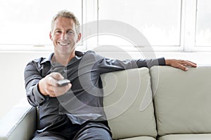 Portrait of single 40s man sitting in sofa tv remote