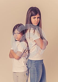 Portrait of sisters standing back to back not talking to each other