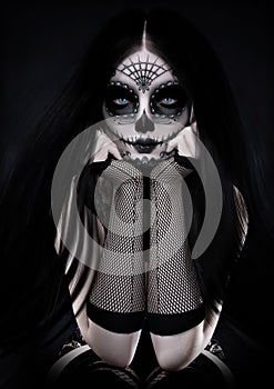 Portrait of a sitting female wearing sugar skull style make up with long black hair and dressed with Gothic accents.