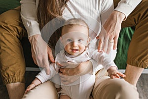 Portrait of a six-month-old baby boy who is hugged by his parents' hands