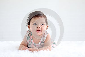 Portrait of six months crawling lovely baby on fluffy white rug with copy space, happy smiling adorable sweet little cute girl kid