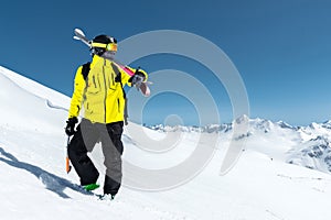 A portrait of a skier in a protective helmet and glasses is a mask and scarf with skis on his shoulder in the snow