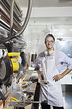 Portrait of a skilled worker standing with hands on hips in workshop