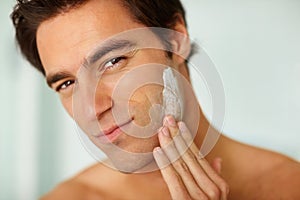 Portrait, skincare and cream with a man in the bathroom of his home for morning routine or treatment. Face, beauty and