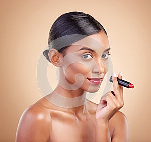 Portrait, skincare and Indian woman with lipstick, beauty and happy against brown studio background. Face, female and