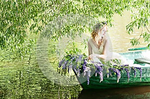 Portrait of slavic or baltic woman with wreath sitting in boat with flowers. Summer