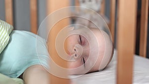 portrait of sleeping infant baby in crib, caucasian child kid is lying in bed,