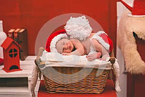 Portrait of sleeping newborn baby boy in Santa clothes.