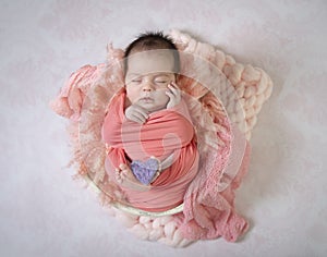 Portrait sleeping newborn baby holding heart between feet