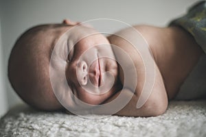 Portrait of sleeping smiling newborn baby close up