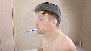 Portrait of sleepy man brushes teeth and falls asleep with toothbrush in mouth.