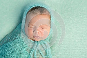 Portrait of sleepy newborn with wrapped head and body