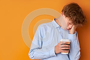 Portrait of sleepy teenager boy with cup of coffee