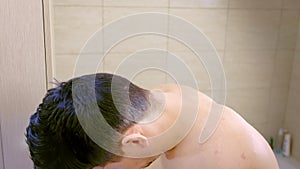 Portrait of sleepy young man sleeping standing in bathroom in early morning.