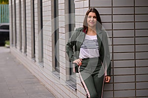 portrait of a slender girl in a green suit in natural light against a white wall. natural beauty, no makeup. problematic skin.