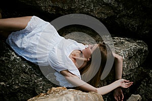 Portrait of slender young woman on stones near the sea