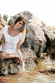 Portrait of slender young woman on stones near the sea