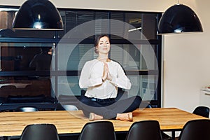 Portrait of slim fit sporty young white Caucasian business woman meditating doing yoga exercises