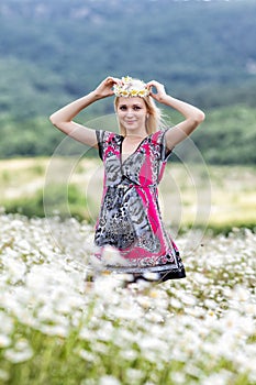Portrait of slim girl in light dress in chamomile field