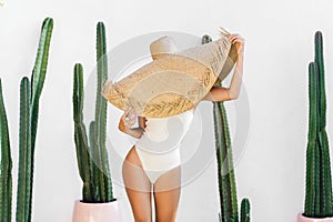 Portrait of a slim young woman in front of a cactus wall.