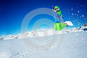 Portrait of a small boy jump on snowboard over sky