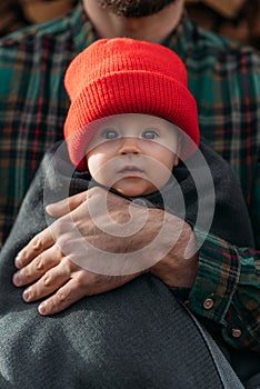 Portrait of a small child in a red hat. A small child in the arms of his father. A beautiful portrait of a child in his arms.