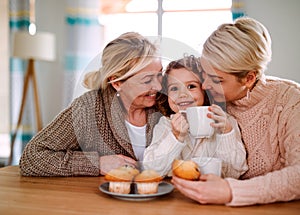 A portrait of small girl with mother and grandmother at the table at home.