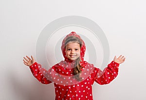 Portrait of a small girl with red anorak in studio on a white background.
