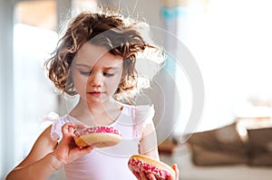 A small girl with doughnuts at home.