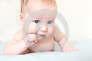 Portrait of small infant kid boy. Child holding head with fist. Baby with confident pensive sight. Serious emotion or expresssion