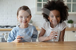 Portrait of small multiracial girls drink mineral water