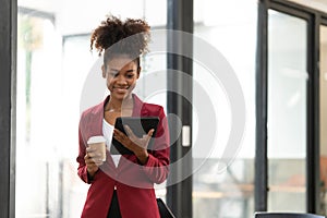 Portrait of smart afro young entrepreneur woman using her digital tablet while standing looking at camera in the office