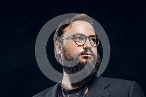 Portrait of a smart bearded man in glasses in a dark studio