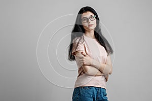 Portrait of smart beautiful brunette girl in eyeglasses with natural make-up, on grey background.