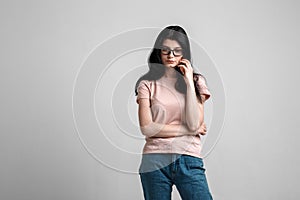 Portrait of smart beautiful brunette girl in eyeglasses with natural make-up, on grey background.
