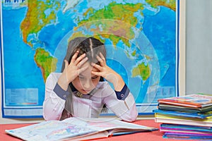 Portrait of a smart cute girl reading books on the background of the world map. The inscription on the map WORLD