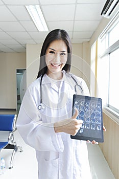 Portrait of smart female doctor holding tablet to show X-Ray picture and standing