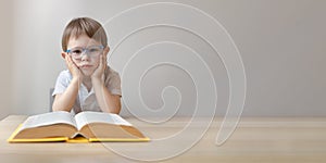 portrait of a smart little boy in glasses with an open book, copy space
