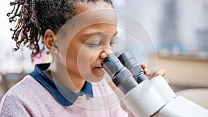 Portrait of Smart Little Schoolgirl Looking Under the Microscope. In Elementary School