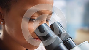 Portrait of Smart Little Schoolgirl Looking Under the Microscope. In Elementary School