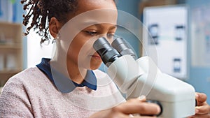 Portrait of Smart Little Schoolgirl Looking Under the Microscope. In Elementary School