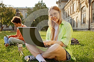 Portrait of smart millennial student using laptop while studying outdoors