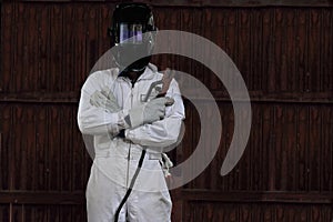 Portrait of smart welder man with torch and protective helmet in white uniform in the factory. Industrial concept.