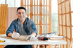 Portrait of a smile Asian male father sitting and working on the table with the instrument of measure and working tools.