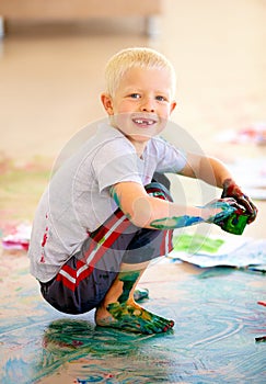 Portrait, smile and boy painting the floor in a studio for art education at school as a creative student. Kids, growth